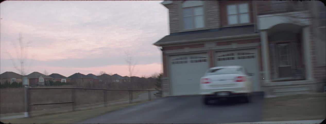 Car travels on a residential road at sunset