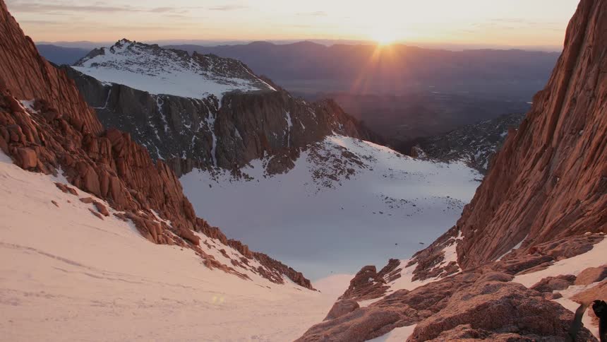 Sun rises over snowy rocky mountains