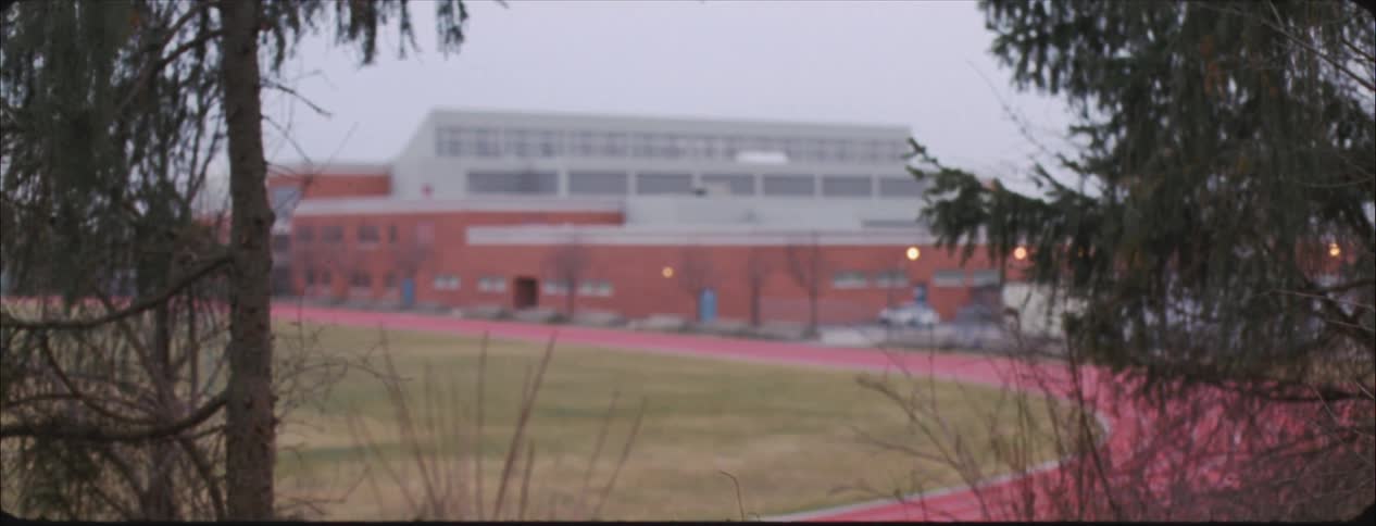 A jogger is running on a track on a campus at dusk