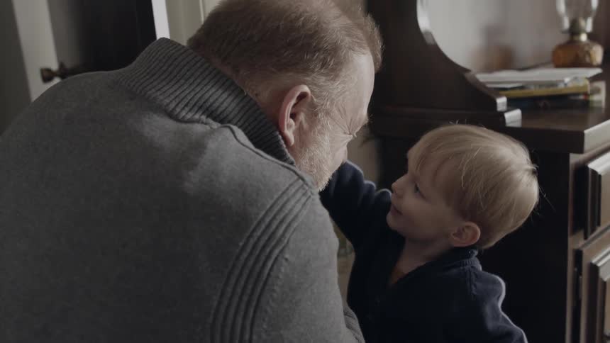 Grandfather and grandson are playing inside home