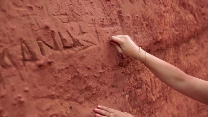 A woman makes markings on the clay wall