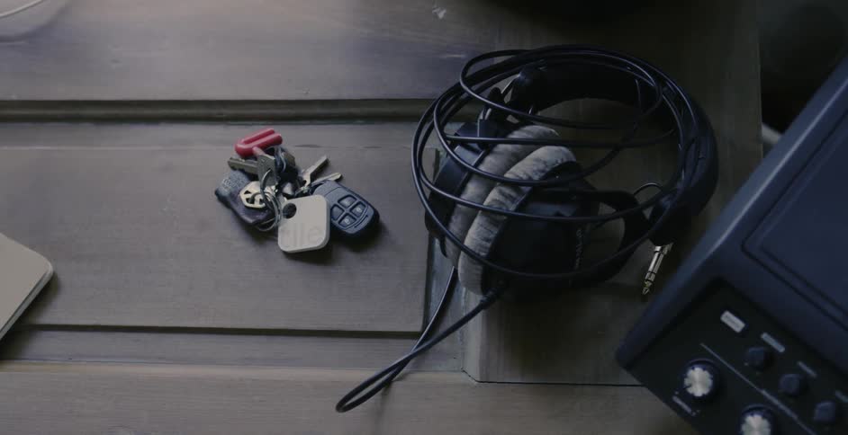 A hand grabs headphones from a table