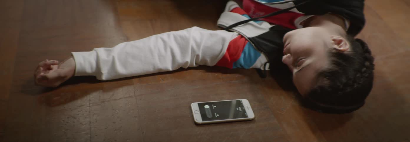 Young boy lays on the floor with a cell phone nearby