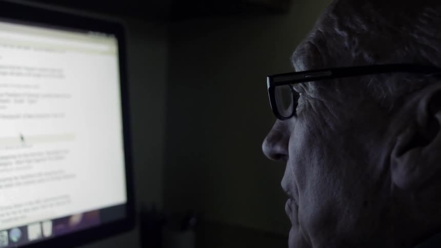 Man sits and talks while looking at a monitor