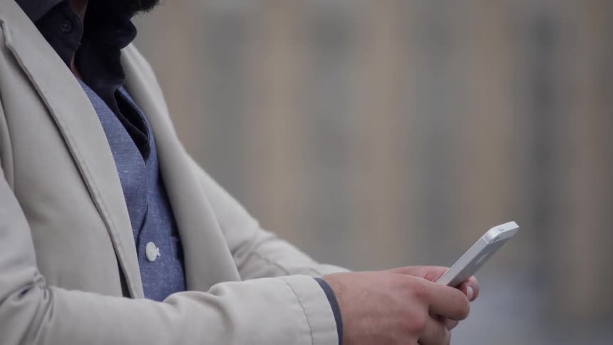 Person reaches into coat pocket and takes out phone