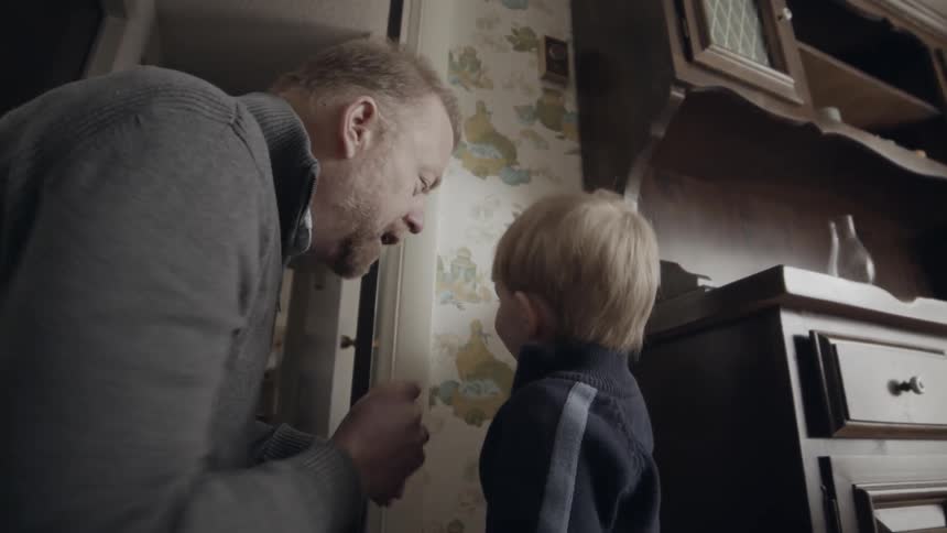 Elderly man and toddler use a pencil to mark on the wall