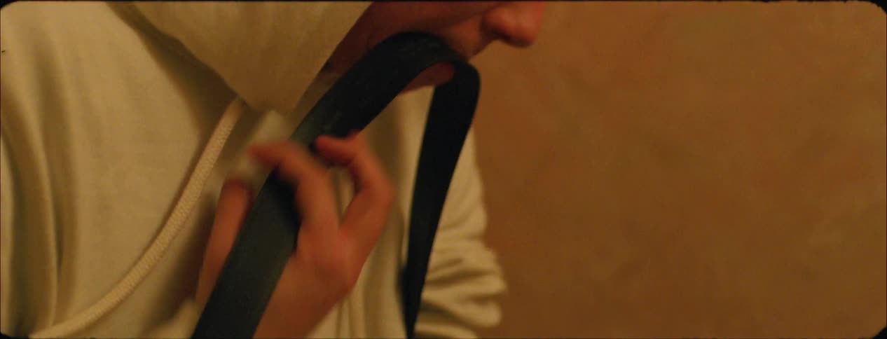 A teenage boy is rolling up one sleeve and preparing to inject himself with drugs