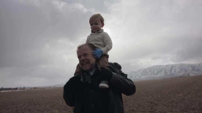 Grandfather is giving grandson a ride on his shoulders on cloudy day