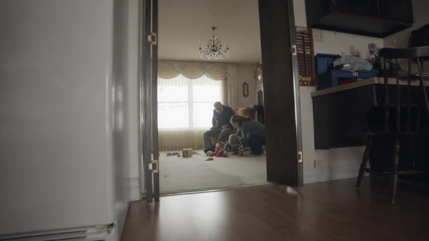 Grandparents are playing with a toddler inside their home in daylight