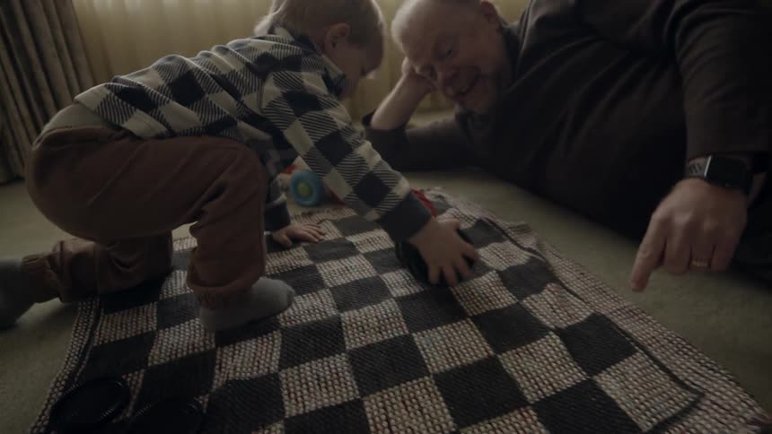 A man and young child play on the floor