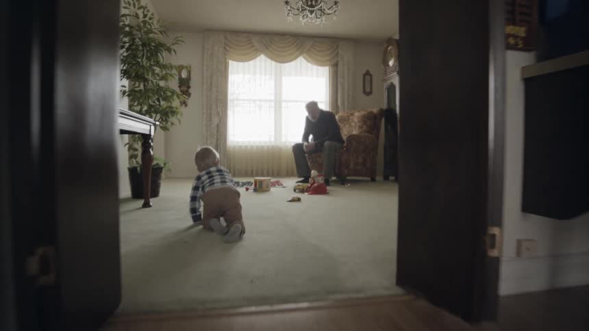 Toddler crawls towards man sitting in armchair