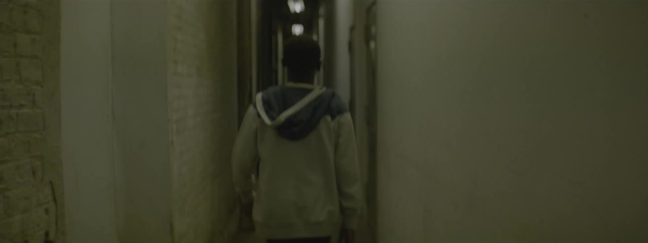 Young man walks down a basement hall and enters a door