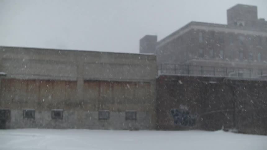 Snow falls outside of a concrete building in an urban area