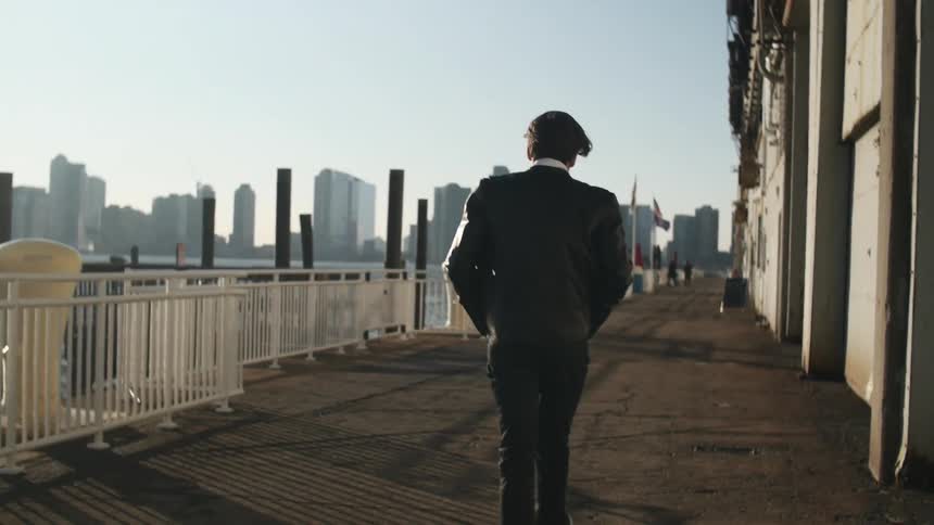 Man walking across a pier with a large building on his side