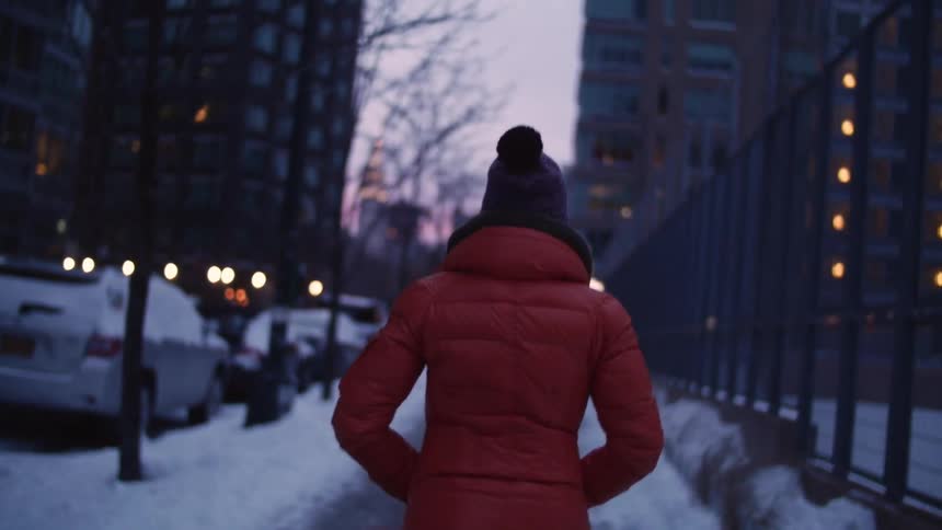 Woman walking down a sidewalk in a city