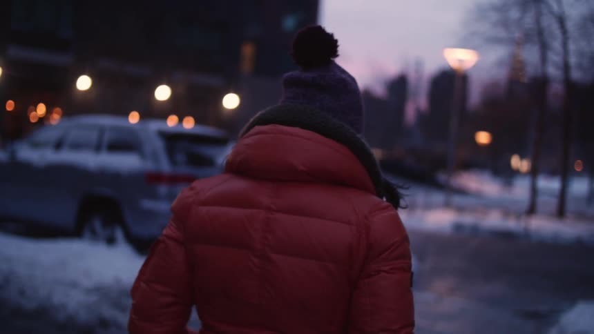 A woman walks through a city at dusk