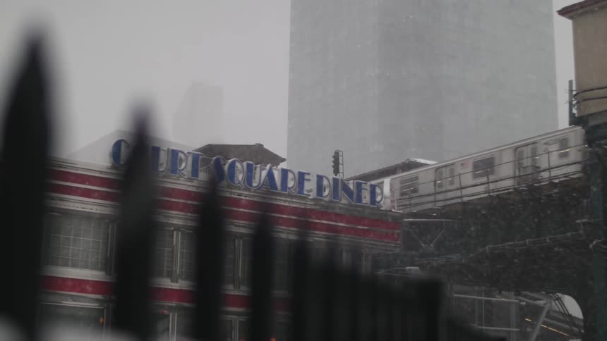 A snowstorm in the city as a train rolls by