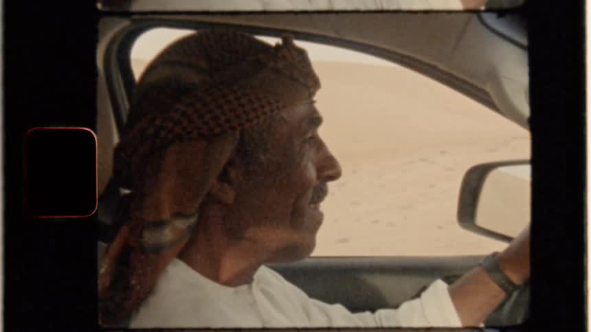 Man waves as he drives a vehicle in the desert