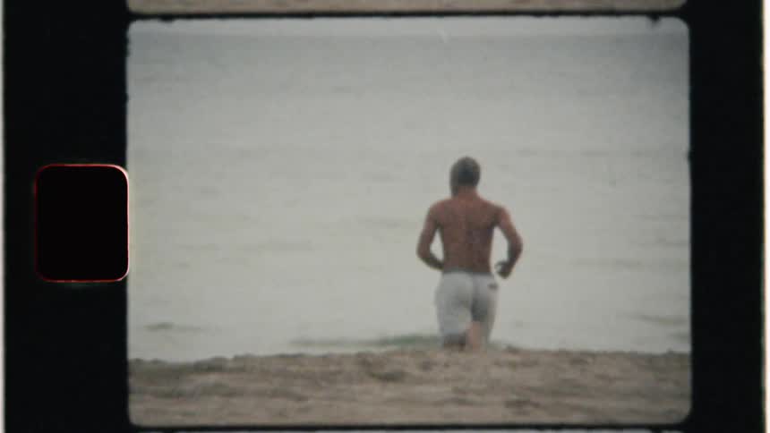 A man runs on the beach toward the ocean