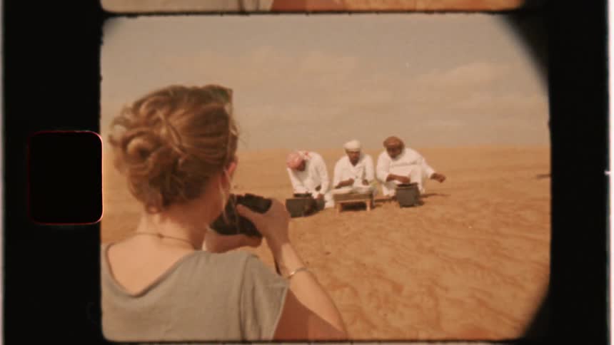 A woman photographs three men in the desert