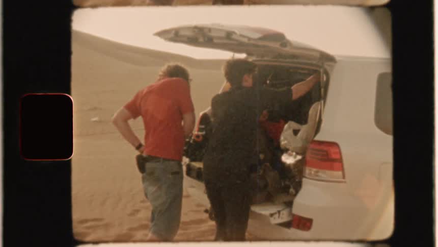 Men stand at the back of a loaded suv in the desert