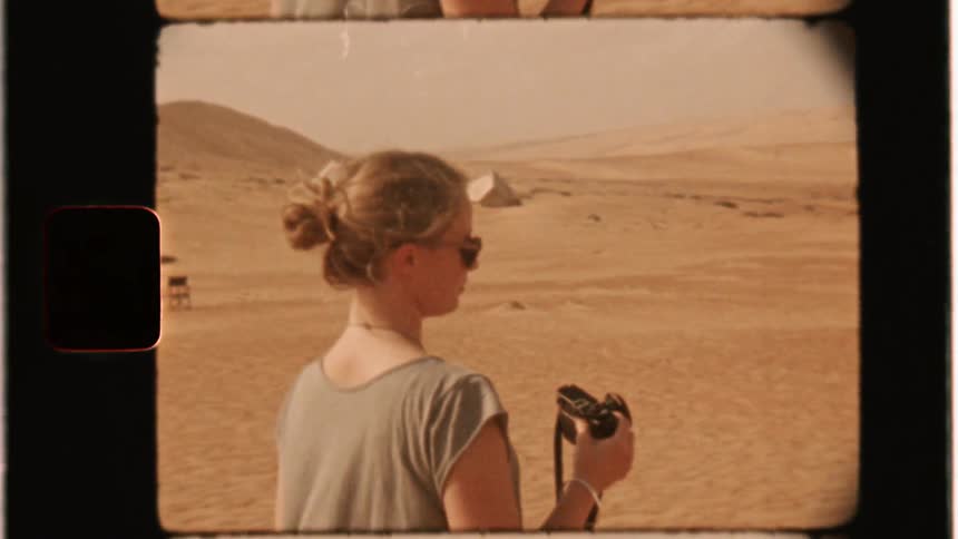 A woman carries a camera in the desert