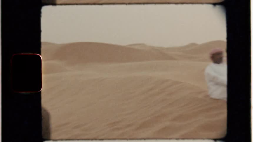 A woman photographs a man in the desert