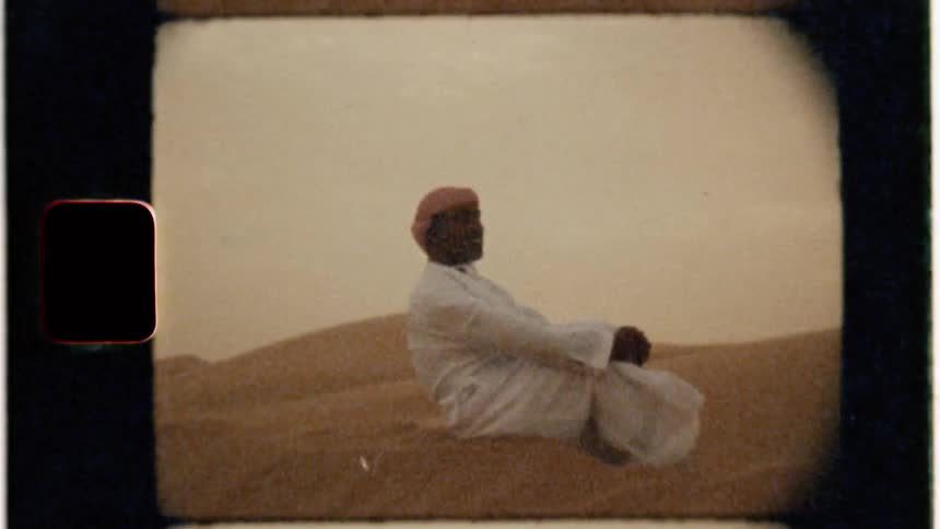 An arab man sits in the desert sand on a windy day