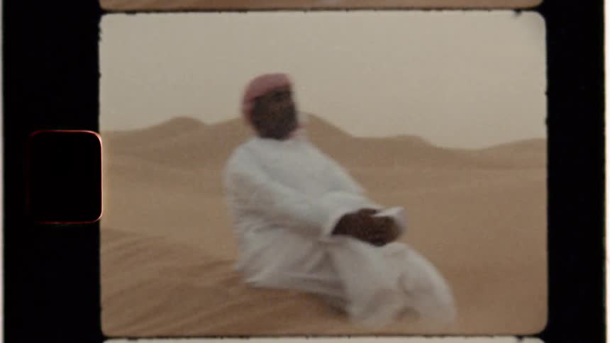 Man sits in a sandy desert on a windy day