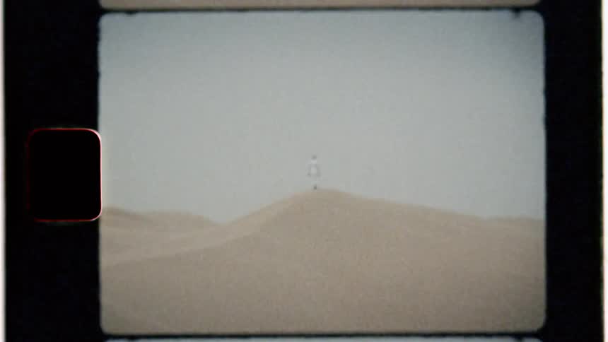 A man stands on a sand dune in a desert