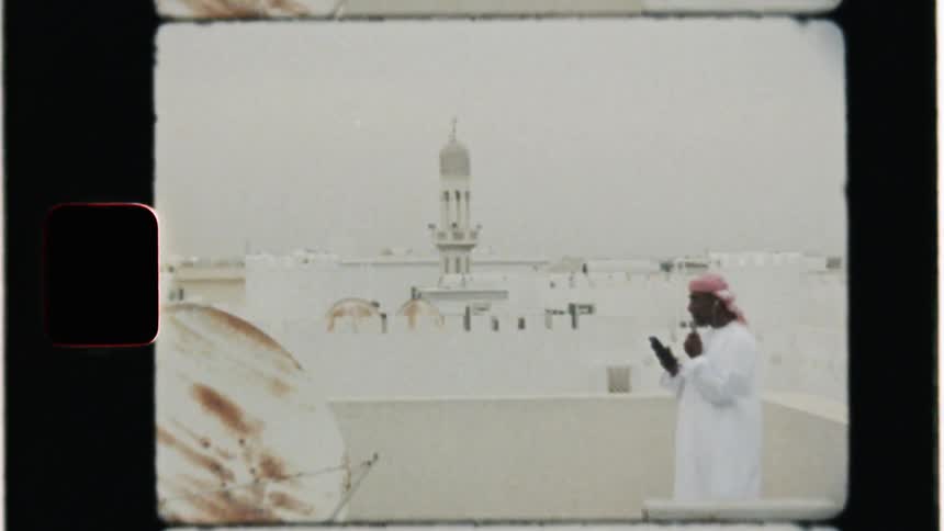 Man stands on a rooftop in a city looking at his phone