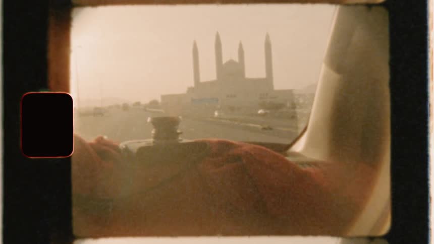 A vehicle is driving on a highway past a mosque in daylight
