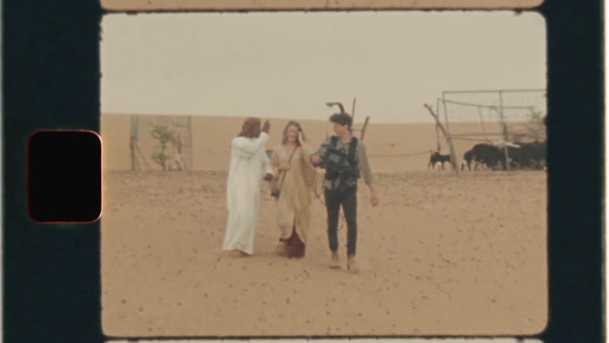 Woman and men walk across a desert