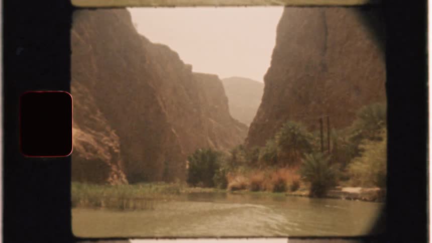 A boat is traveling on a river in a desert landscape in daylight