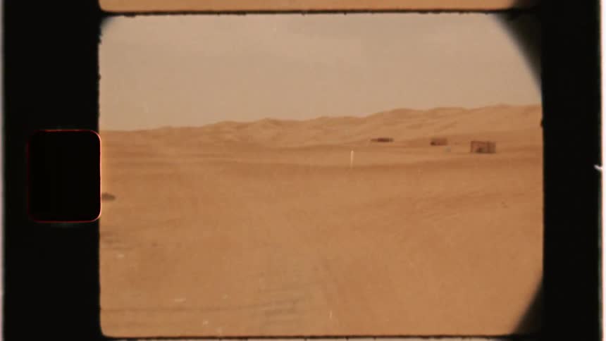 A vehicle drives in a desert