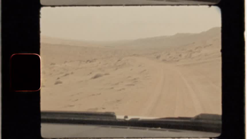 A vehicles is driving through a desert landscape in daylight