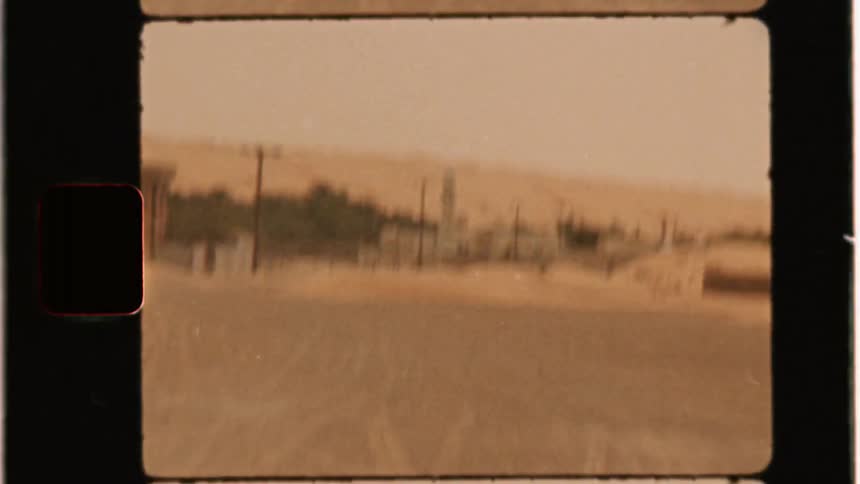 A desert village with sand dunes behind it