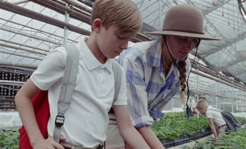 A boy and woman look at plants in a nursery