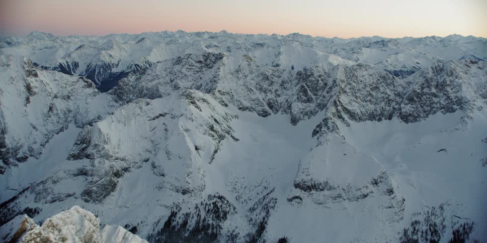 The sun sets over snowy mountains