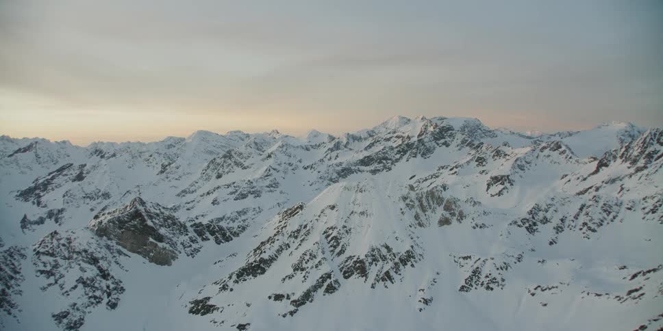 The sun sets over snowy mountains
