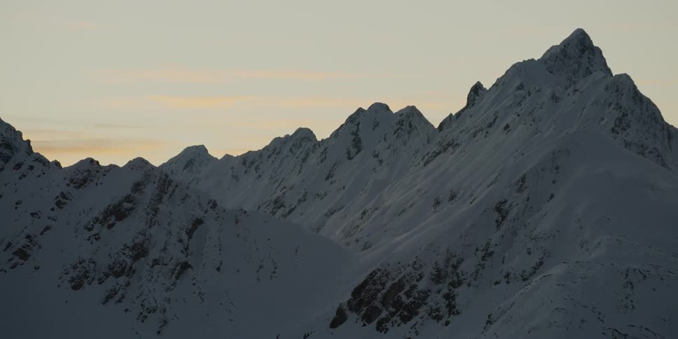 The sun sets over snowy mountains