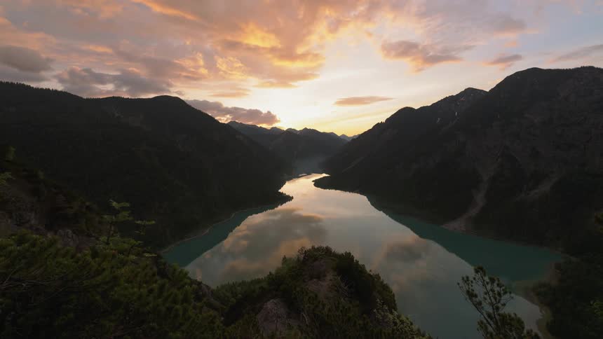 Sun sets behind hills and a large lake