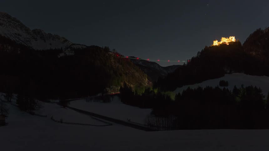 Vehicles driving on a winding road through the mountains at night