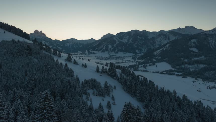 The sun rises over a snow covered ridge and slopes