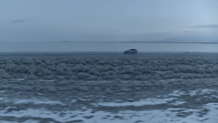 A car drives on a rural road at dawn