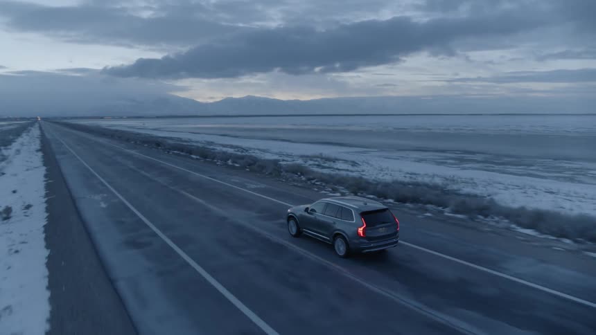 Car drives down a snowy country road at sunrise