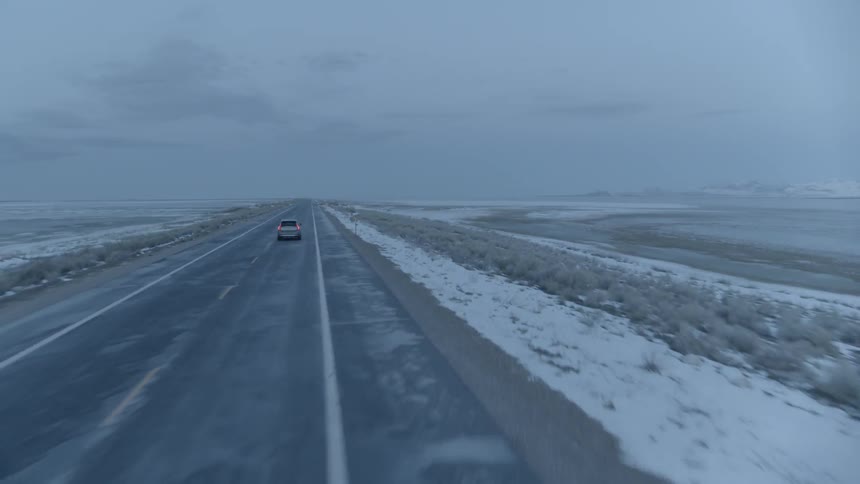 An suv travels on a rural road on a gray day