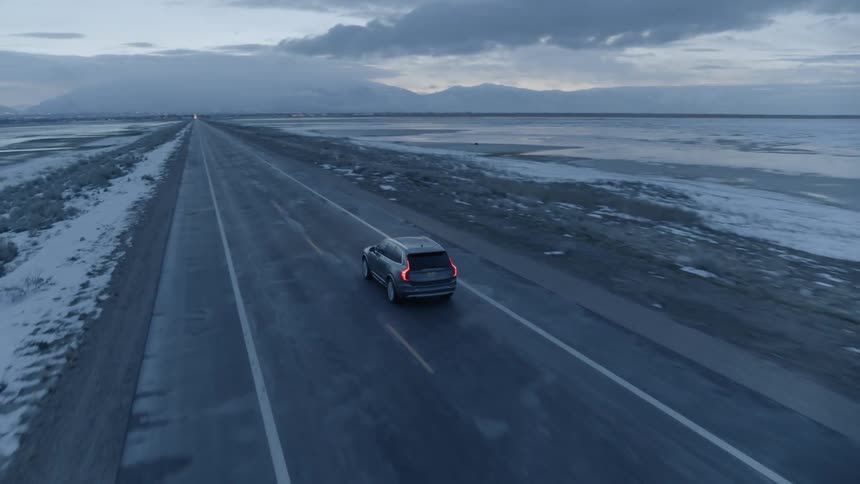 A car travels on a rural road at sunset