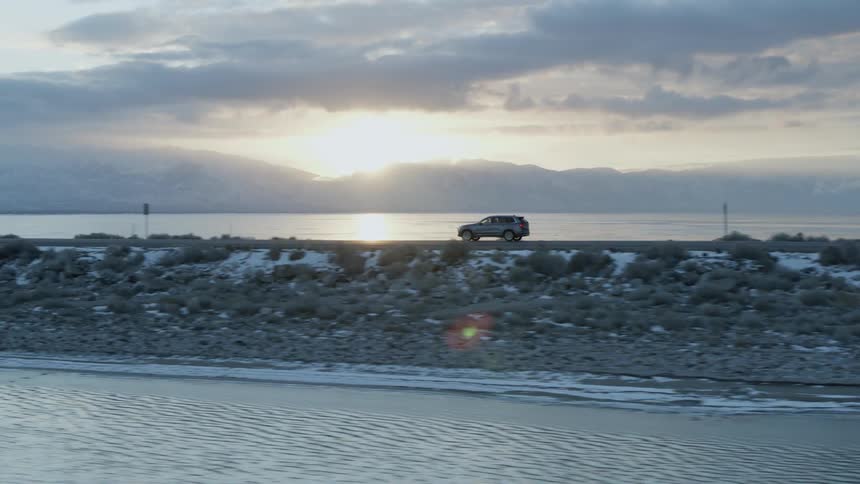 Car drives down a road in between a large body of water