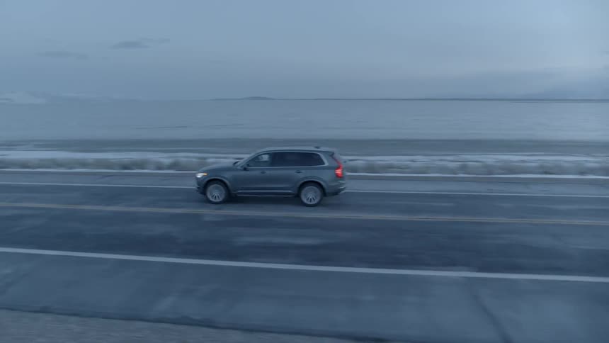 Vehicle travels down a highway under a cloudy blue sky
